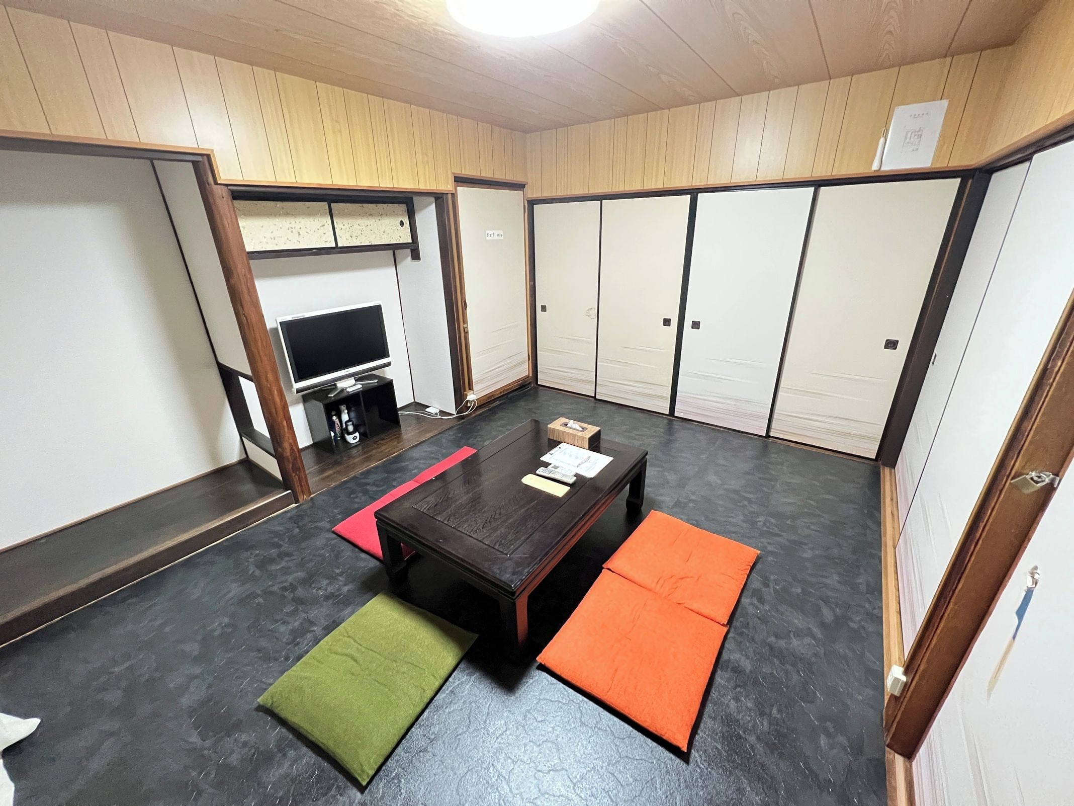 Una habitación con televisión, una mesita y un sofá.