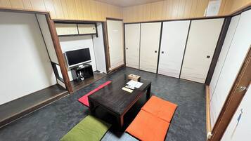 Una habitación con televisión, una mesita y un sofá.