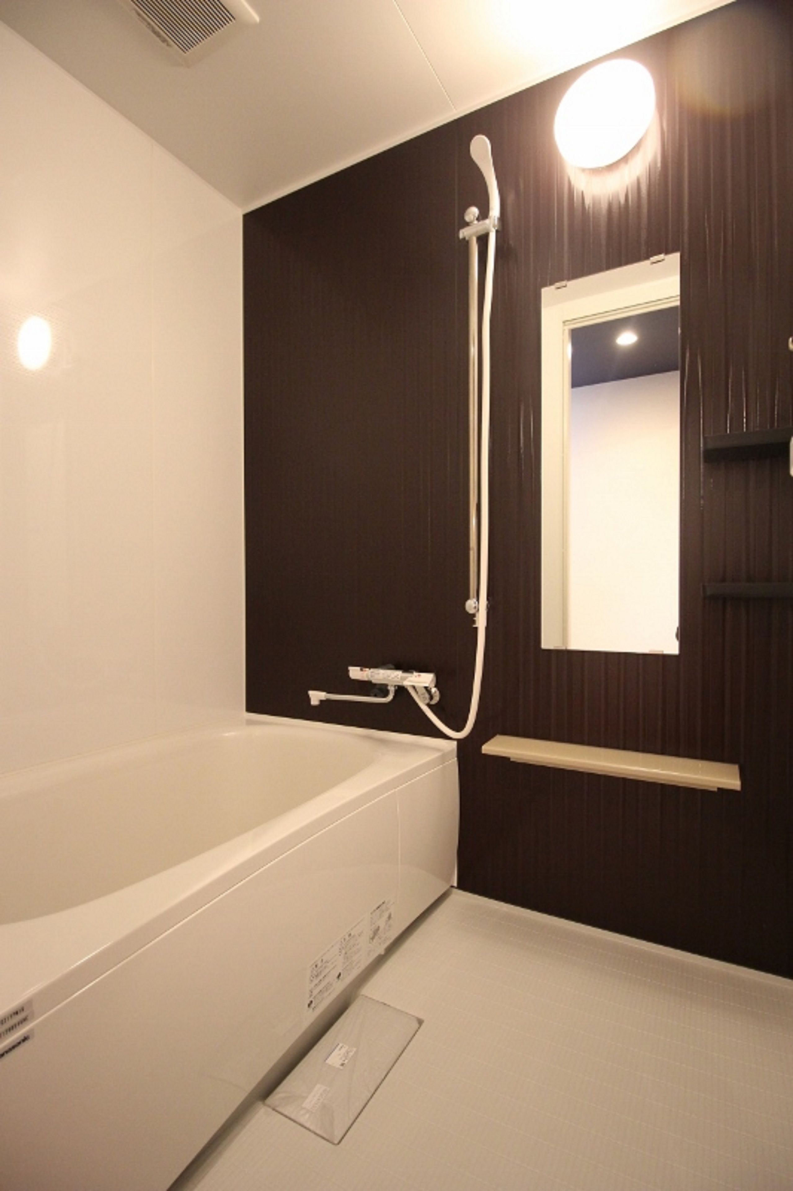 A bathroom with a bathtub, a shower, a mirror, and a towel rack.