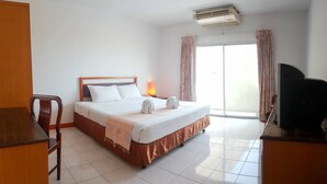 A hotel room with a bed, a desk, a chair, a TV, and a window with curtains. - Eastiny Bella Vista Hotel (Pattaya)