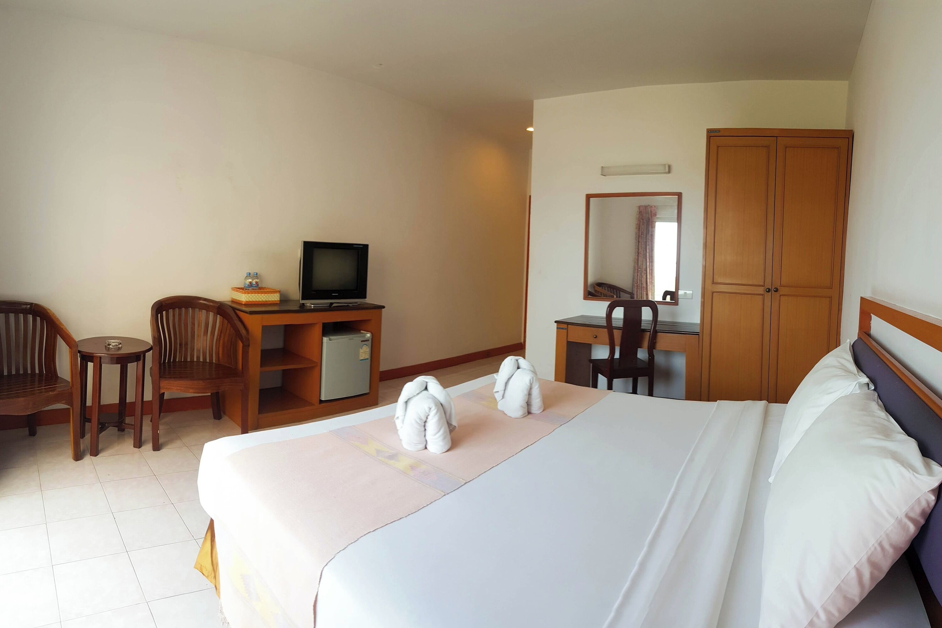 Habitació d'hotel amb un llit, escriptori, televisió i un armari.