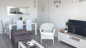 Ein modernes Wohnzimmer mit Sofa, Couchtisch, Fernseher und Essbereich.