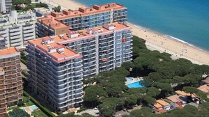 Ein Hochhotel mit mehreren Balkonen, einem Pool und Blick auf den Strand.
