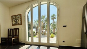 Une pièce spacieuse dotée d’une grande porte-fenêtre coulissante qui donne sur un espace extérieur agrémenté de palmiers.