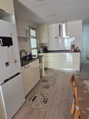 Een moderne keuken met witte kasten, een roestvrijstalen afzuigkap en een vloerkleed met een patroon.