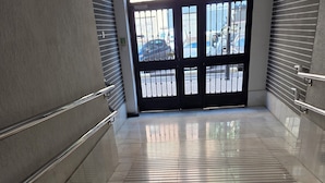 A corridor with a tiled floor, metal railings, and a double door with a sign above it. - Urban Oasis & Private Terrace. (València)