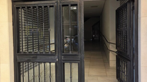 A set of black metal gates with vertical bars and a small window, leading to a tiled staircase. - Urban Oasis & Private Terrace. (València)