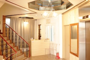Enter the ORASTAY lobby, featuring a staircase, reception desk, and seating area.