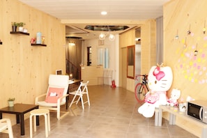 Relax in a comfortable room with a seating area, featuring a chair and table, and a fun touch of a large Hello Kitty plush toy.