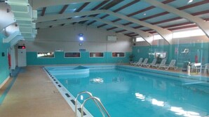 An indoor swimming pool with clear lanes, a lifeguard station, and lounge chairs along the side. - Beach View - Kingsdown Resort (Kingsdown)