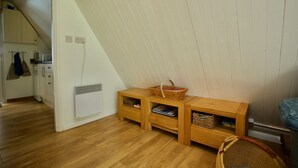 A room with a sloped ceiling, wooden flooring, a small kitchenette, and a wooden bench with storage drawers. - Beach View - Kingsdown Resort (Kingsdown)