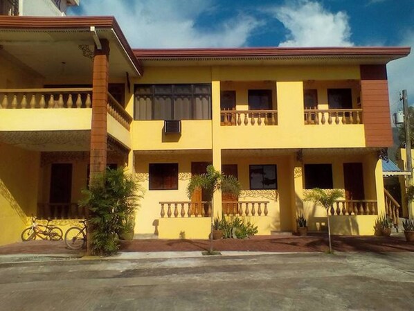 A two-story building with a yellow facade, balconies, and a red roof. - Canoe Beach Resort (San Antonio)