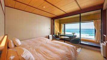 A hotel room with a bed, a small table, two chairs, a view of the ocean, and a large window.
