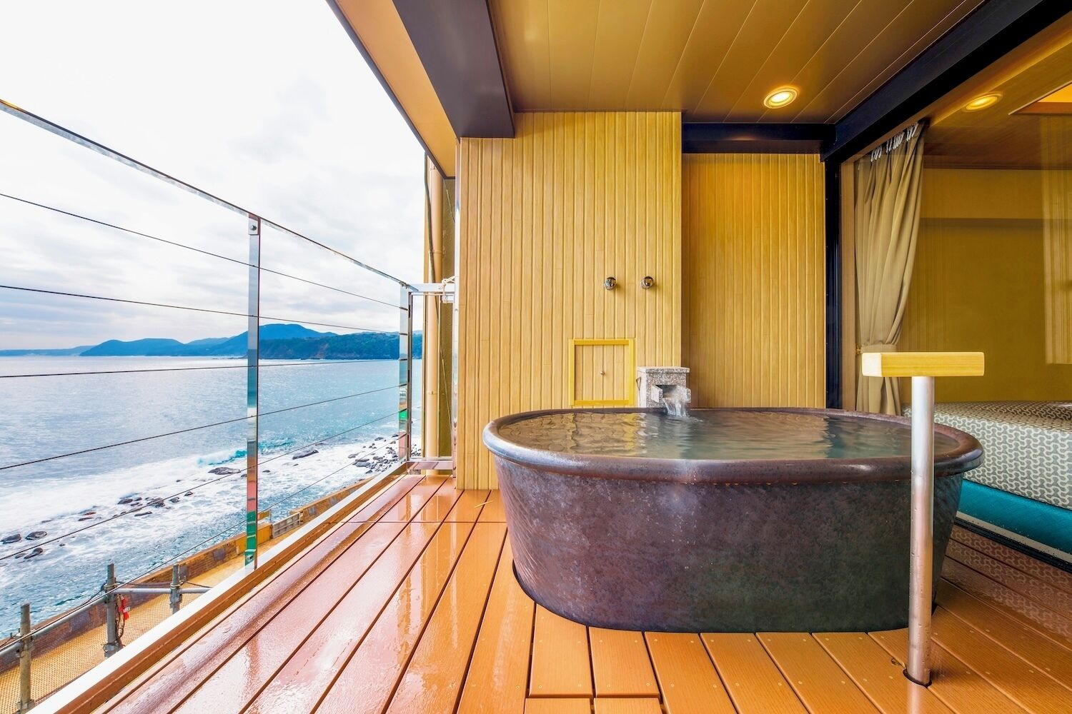 Un jacuzzi en un balcón con vistas al mar y a las montañas.