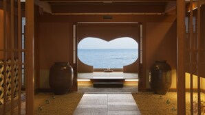 A traditional Japanese room with tatami flooring, a large window with a heart-shaped view of the sea, and two large vases. - Senoumi (Higashiizu)