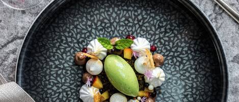 Un plato de postres con diversos dulces y frutas sobre una bandeja oscura y texturizada.