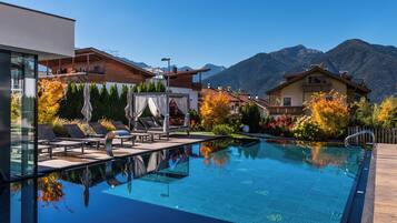 Alberca techada, alberca al aire libre y sombrillas en la alberca