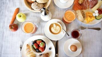 Un desayuno con cruasanes, huevos, café y diversas frutas y verduras sobre una mesa.
