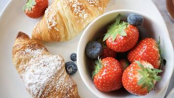 En tallrik med croissanter och en skål med jordgubbar och blåbär.