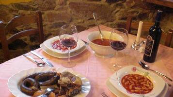 A table set with plates of food, glasses of red wine, and a bottle of wine.