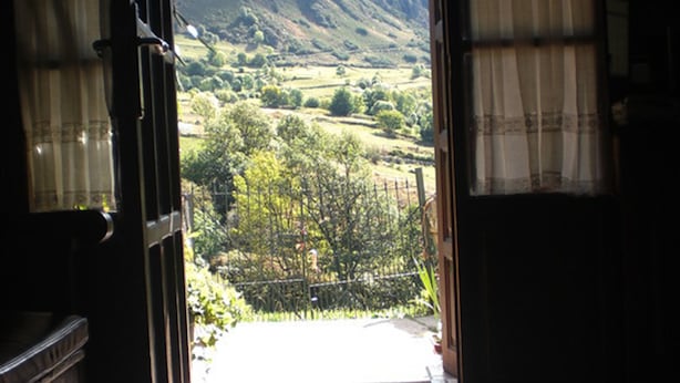An open doorway leading to a scenic outdoor view with a tiled floor and a hanging light fixture. - Hotel Rural Genestoso (Cangas del Narcea)