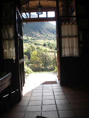 An open doorway leading to a scenic outdoor view with a tiled floor and a hanging light fixture. - Hotel Rural Genestoso (Cangas del Narcea)