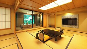 A traditional Japanese room with tatami flooring, a low table, sliding glass doors leading to a garden, and a mounted TV. - Kagiya the annex of Senoumi (Minamiizu)