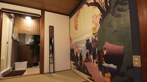 Una habitación tradicional japonesa con suelo de tatami, una puerta corredera shoji y un gran mural que representa una escena histórica.
