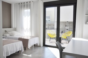 A hotel room with two beds, a balcony with yellow chairs, and a view of buildings. - Residencia Universitaria Resa Tarragona Mediterrani - Campus Accomodation (Tarragona)