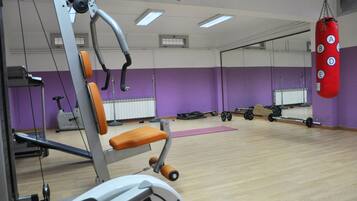 Een sportschool met trainingsapparatuur, een bokszak en een spiegelwand.