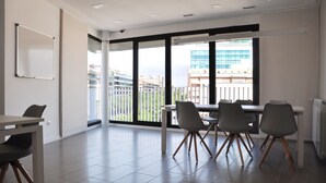 Una sala de reuniones moderna con una mesa grande y sillas, ventanas amplias con vista a edificios, y una pizarra en la pared.