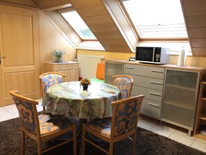 A compact kitchen with a round table, two chairs, a microwave, and a cabinet. - Gästehaus Monika (Hornbach)