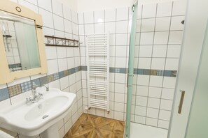 Ein Badezimmer mit Waschbecken, Spiegel, Dusche und gefliesten Wänden.