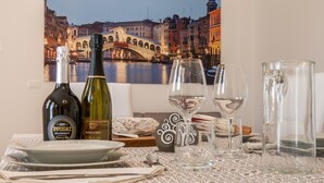 A table set with wine bottles, glasses, and a pitcher, with a cityscape view in the background. - Cimadolmo Prosecco and History (Cimadolmo)