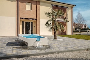 A modern building with a pool, a palm tree, and a brick facade. - Cimadolmo Prosecco and History (Cimadolmo)