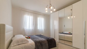 A modern bedroom with a large bed, a bedside plant, and a mirror cabinet. - Cimadolmo Prosecco and History (Cimadolmo)