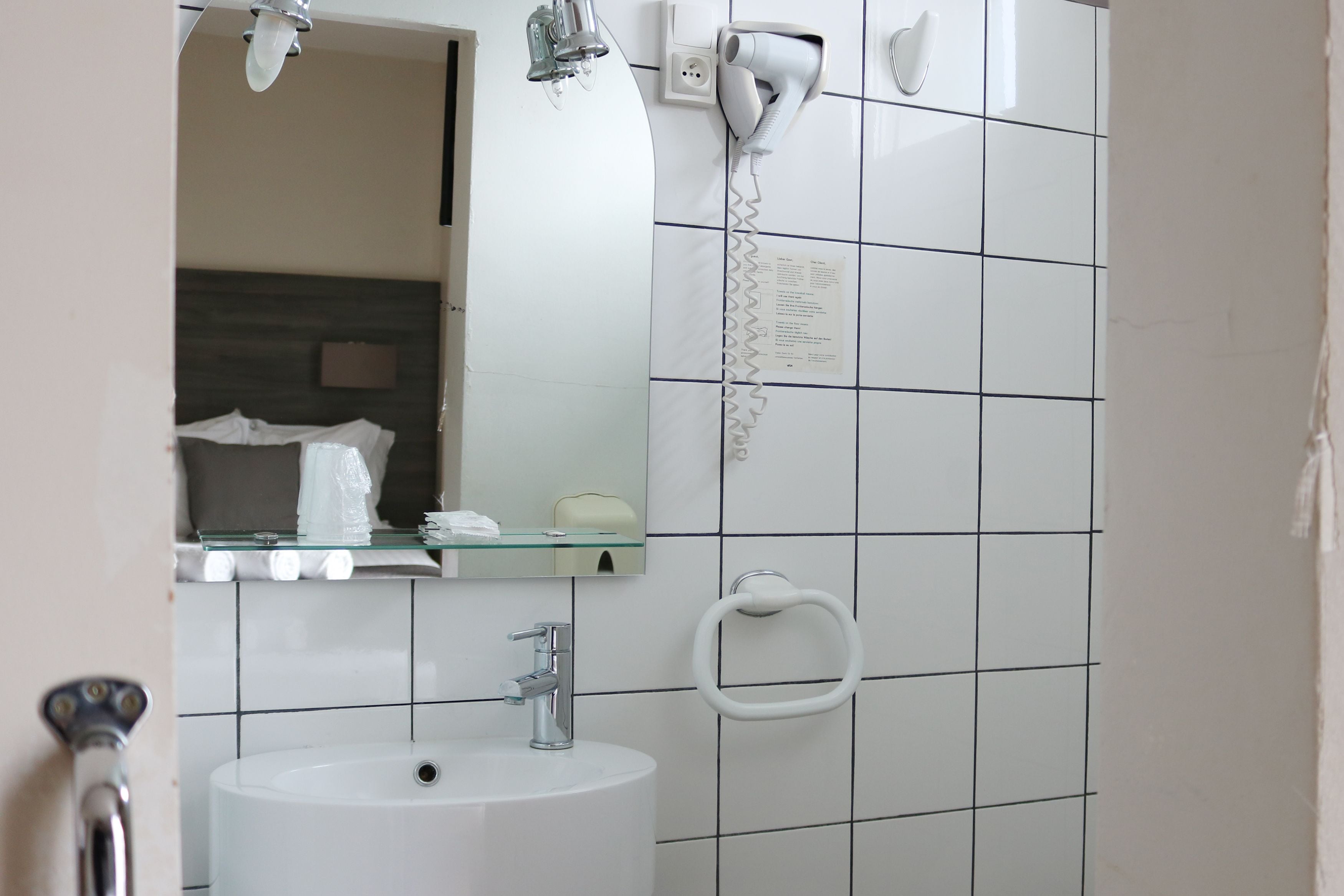 A bathroom with a sink, mirror, towel rack, and a hairdryer on the wall.