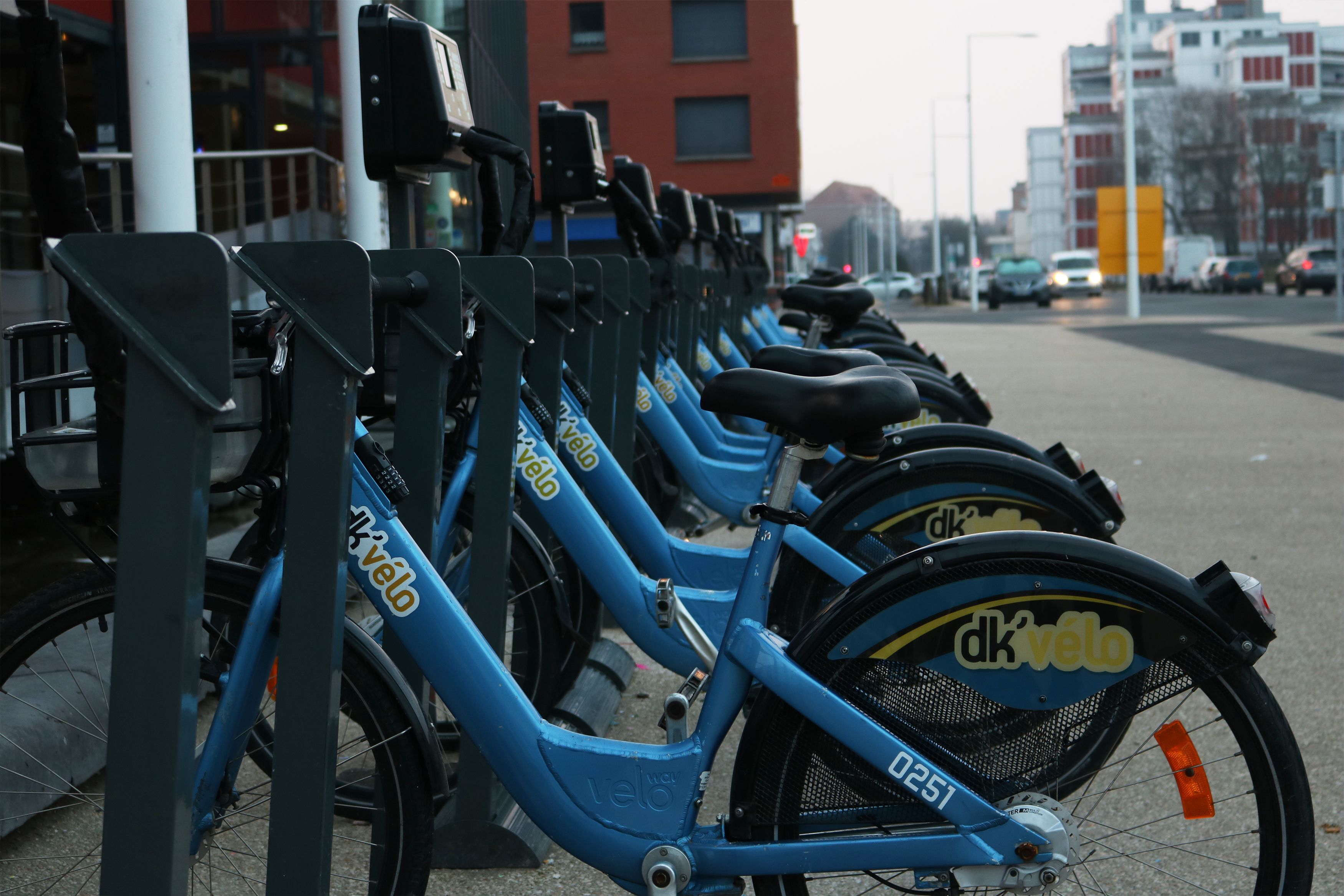 Une rangée de vélos bleus est stationnée devant une borne d’un service de vélos en libre-service.