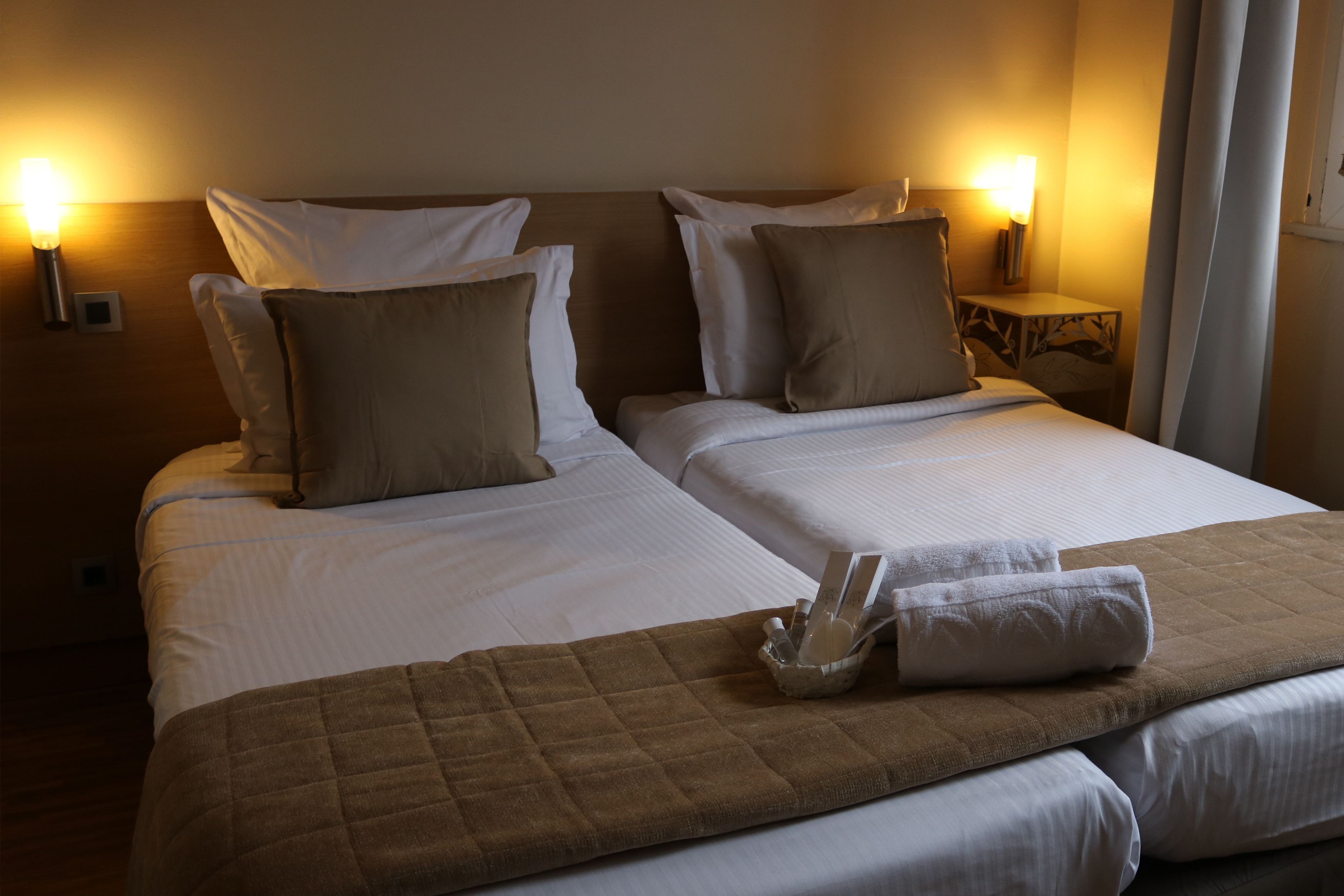 Una cama doble con dos almohadas, un edredón acolchado marrón y una mesita de noche con una lámpara.
