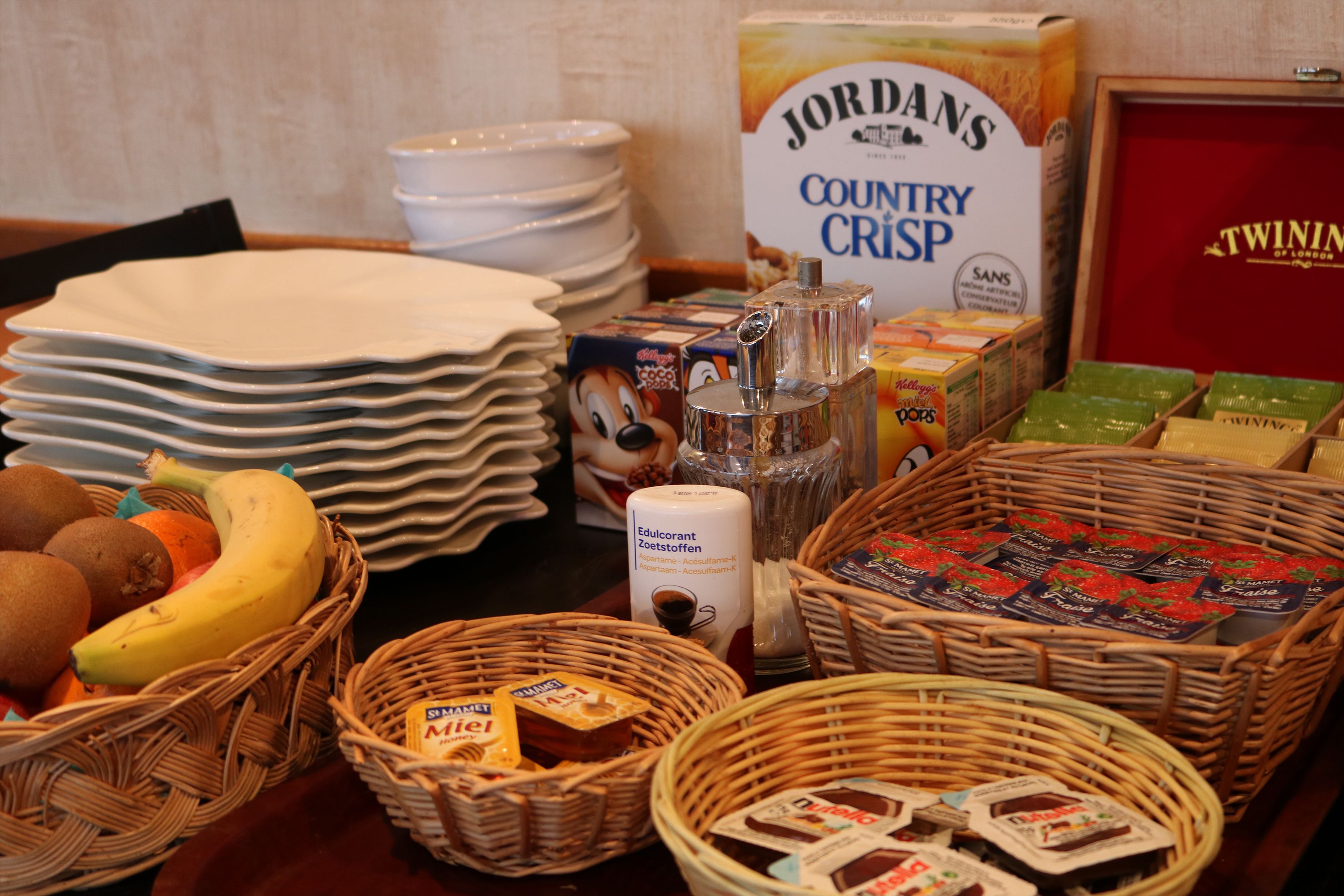 Ein Frühstücksbuffet mit verschiedenen Speisen, darunter Obst, Gebäck und Müslischalen.