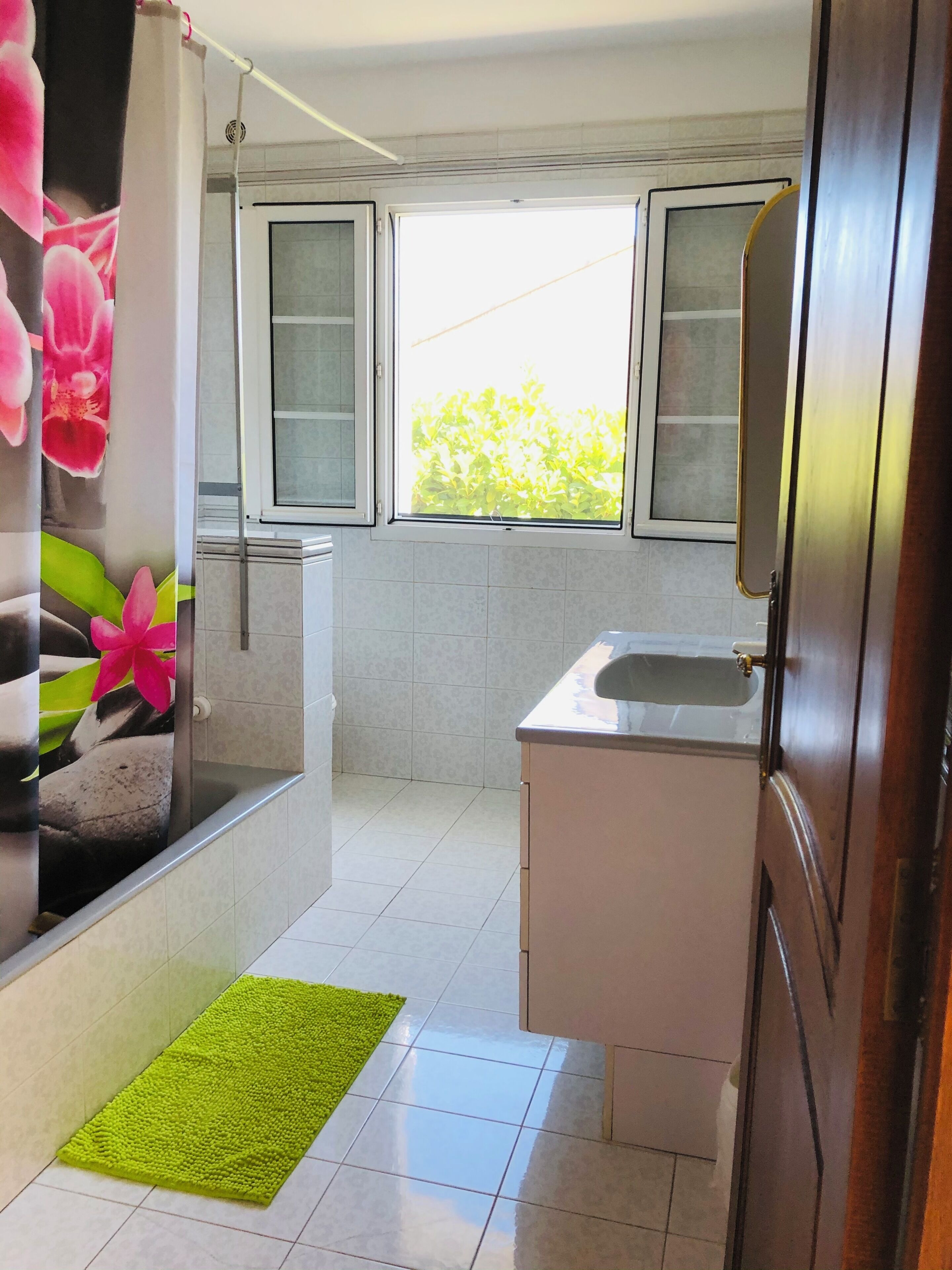 A bathroom with a shower, a sink, and a window.
