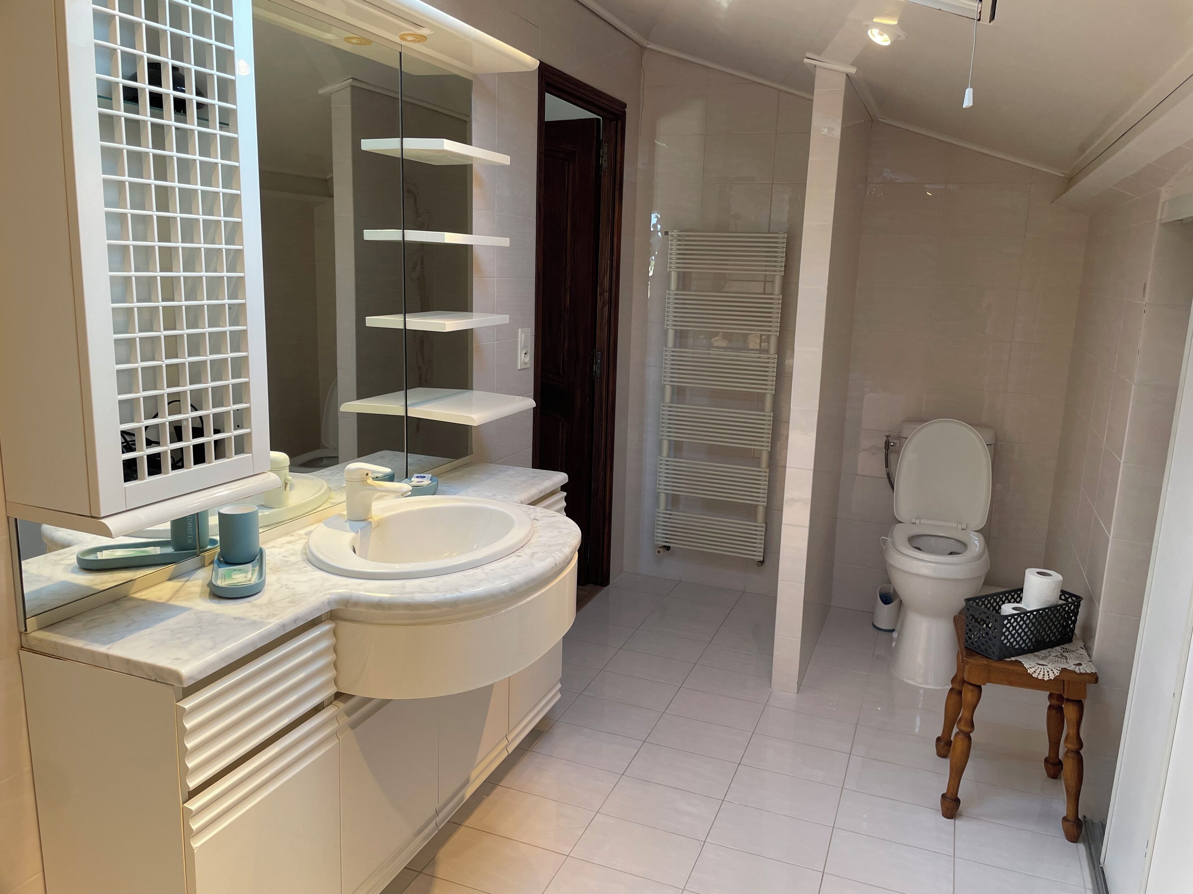 Ein modernes Badezimmer mit einem weißen Waschtisch, einem großen Spiegel und einer Toilette.