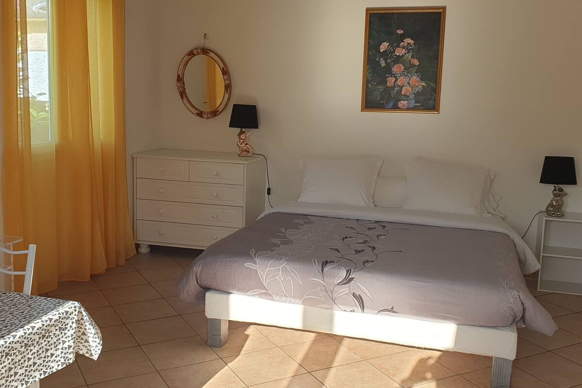 Un dormitorio con cama, cómoda, televisor y un cuadro en la pared.