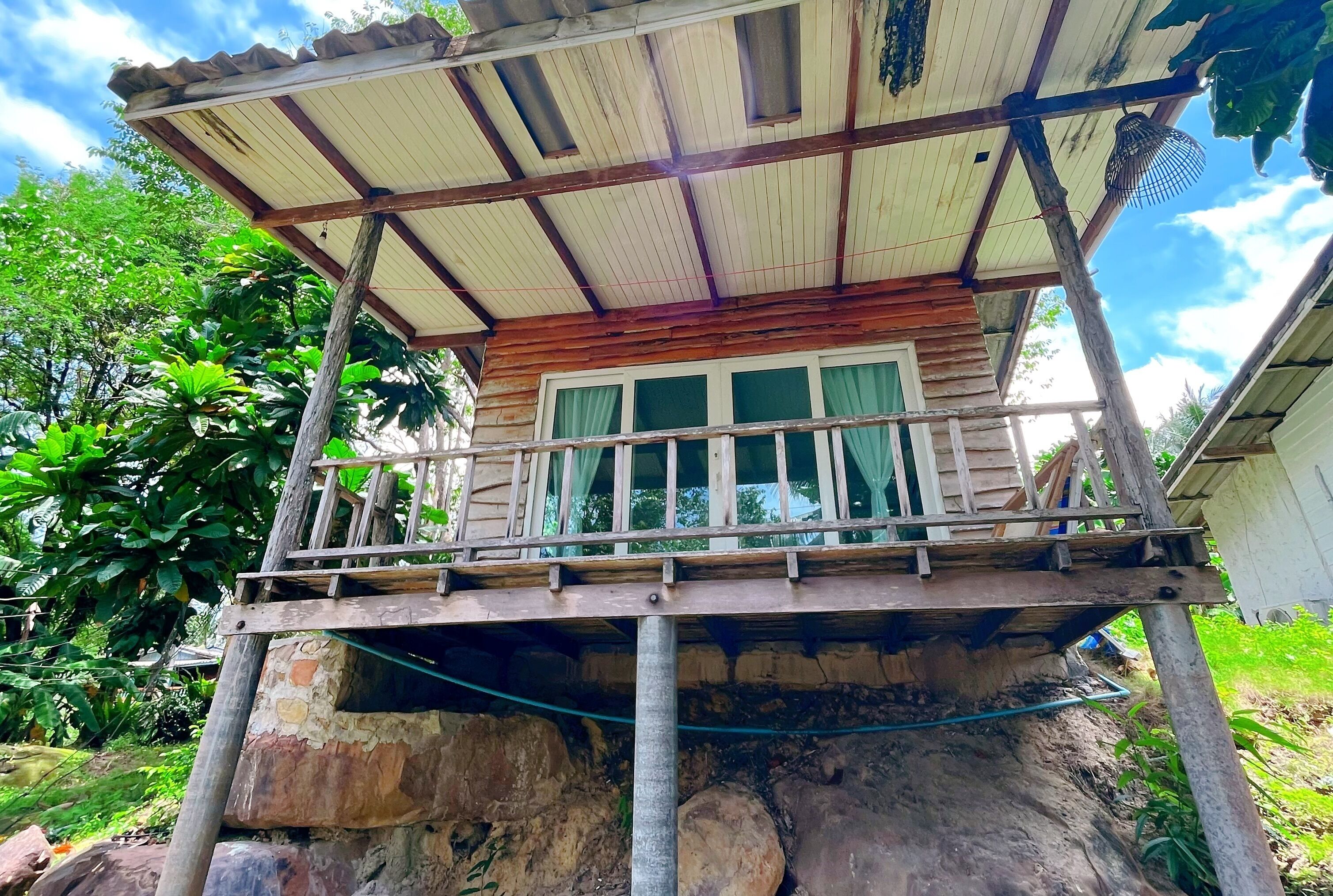 A rustic wooden structure with a balcony, supported by metal beams and a corrugated metal roof.