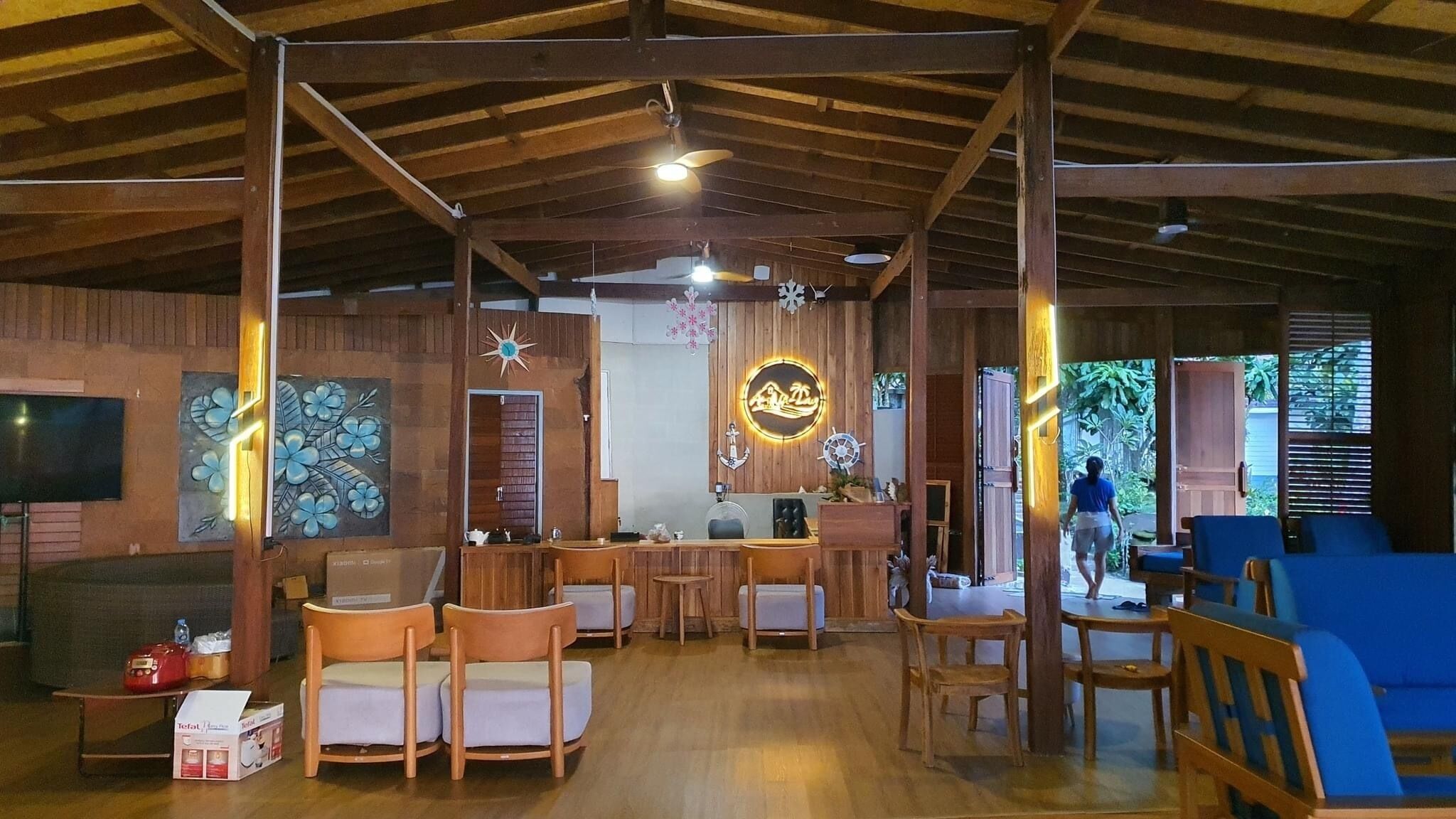 A wooden interior with a bar area, seating, and a neon sign.