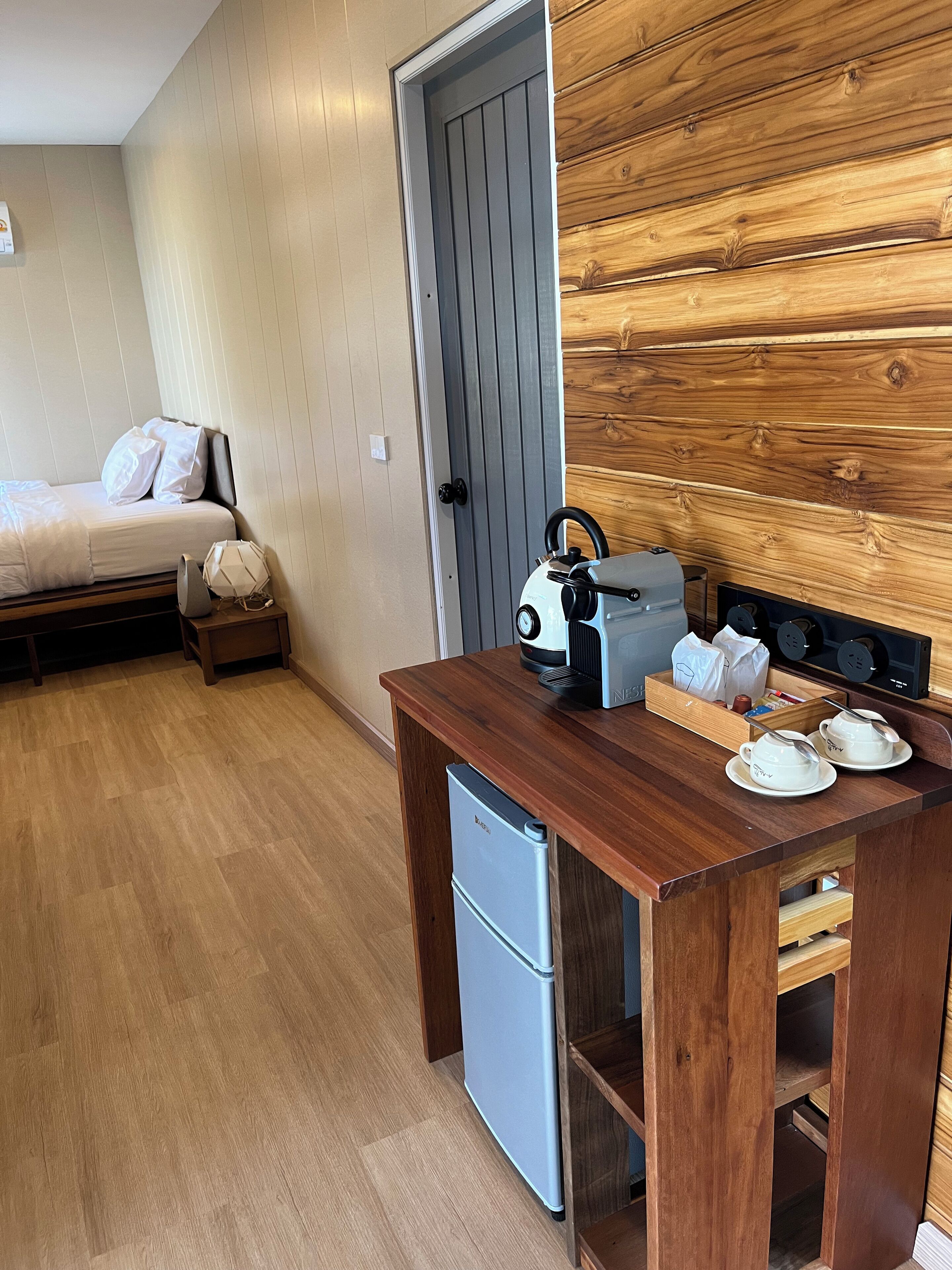 Ein kompakter Raum mit einem Bett, einer kleinen Küchenzeile und einer Holzwand.