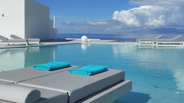 A modern pool area with lounge chairs and a view of the sea.