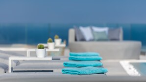 A modern lounge area with a pool, a white table with a cactus, and blue towels.