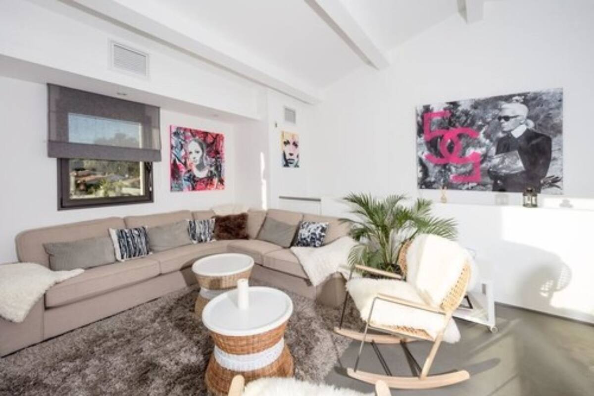 Una sala moderna con un sofá, mesas redondas tipo centro y un sillón mecedora.