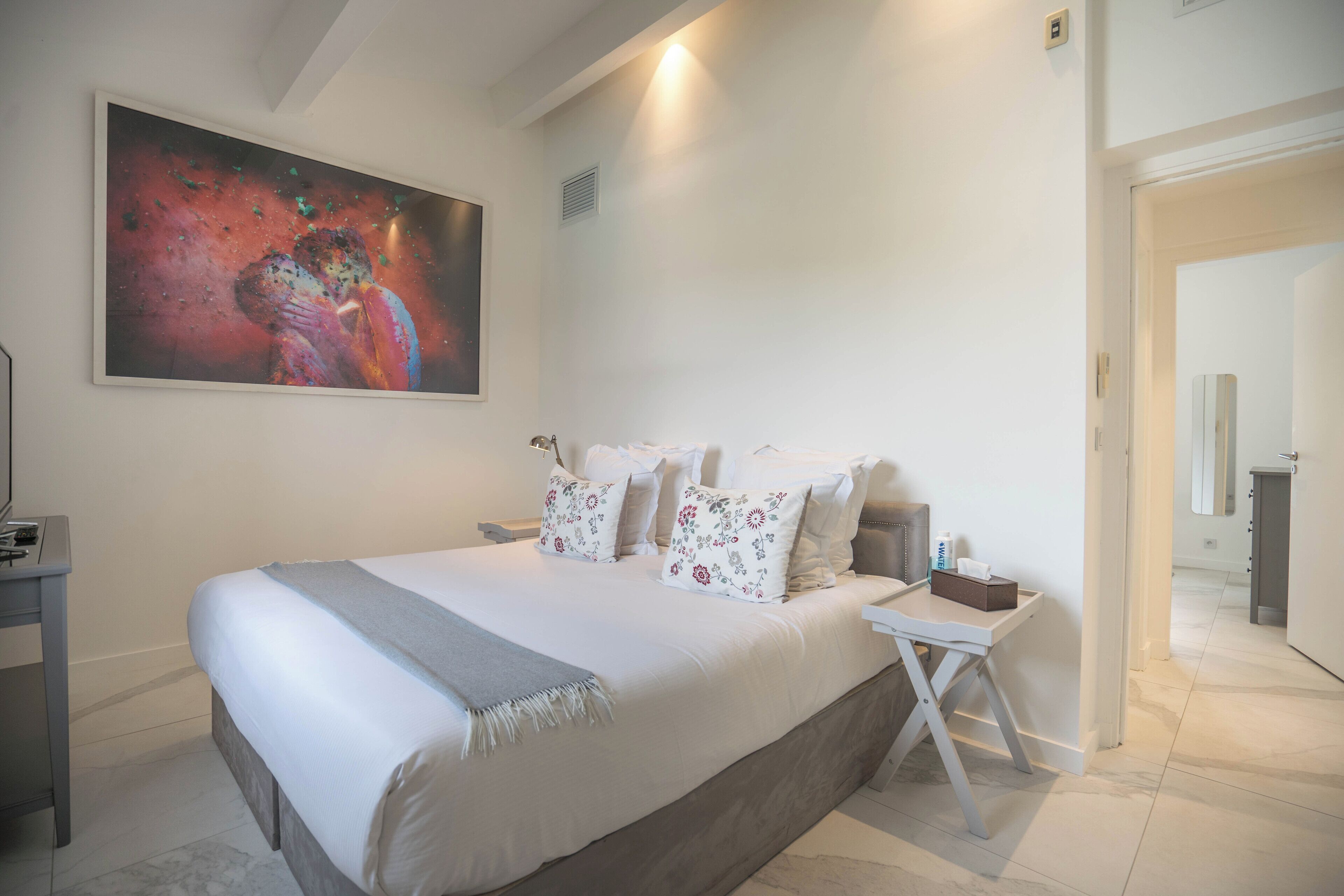 Quarto com uma cama grande, uma escrivaninha e um quadro na parede.